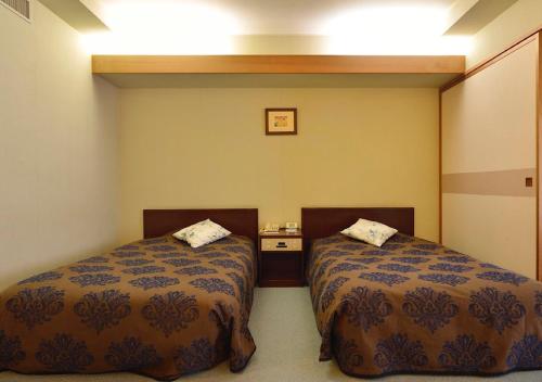 a room with two beds and a table at Mashikokan Satoyama Resort Hotel in Mashiko