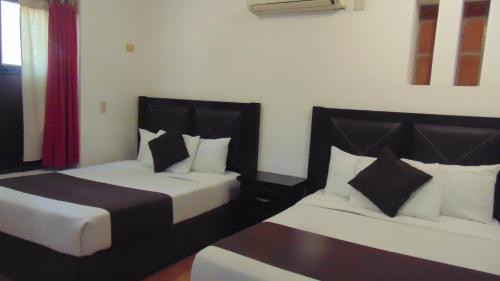 a hotel room with two beds and a red curtain at Hotel Quinta Minera in Cosalá