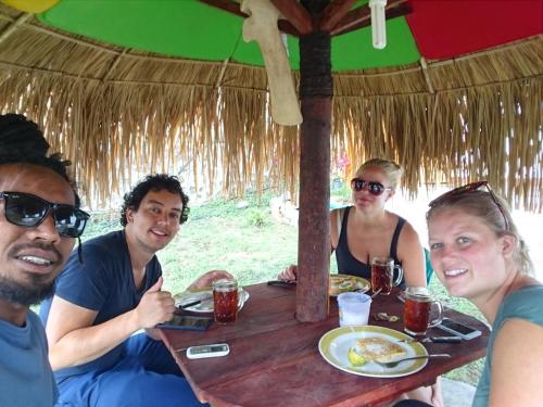 a group of people sitting at a table with food at Mahoni Guest House in Kelimutu