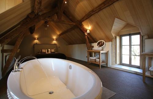 a large white tub in a room with a bedroom at Domaine de la Fouardière in Mulsans