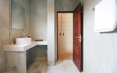 La salle de bains est pourvue d'un lavabo et d'une porte en bois. dans l'établissement Unique Loft Apartment, à Kamala Beach