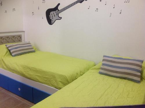 1 dormitorio con 2 camas y una guitarra en la pared en Ushuaia centro Complejo de Cabañas en Ushuaia