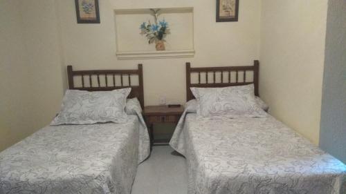 1 dormitorio con 2 camas y mesa en Hostal Alameda en Mérida