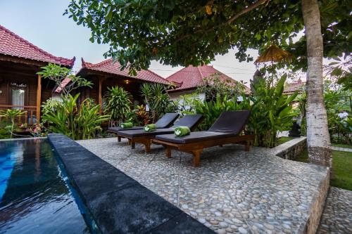 een resort met een zwembad en een bank naast een huis bij Putra 7 Cottage in Nusa Lembongan