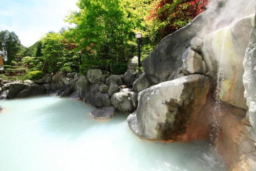 a waterfall in a river with rocks at Hotel Mahoroba in Noboribetsu