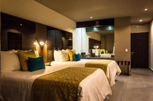 a hotel room with two beds and a mirror at KABAH Cancun Hotel Boutique in Cancún
