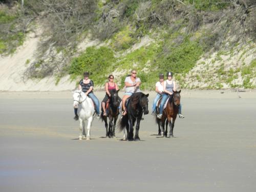 a group of people riding horses on the beach at Gill's Beach House in Chintsa