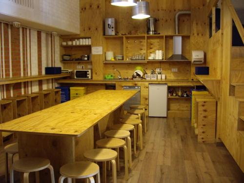 a large kitchen with a large wooden counter and stools at O Albergue de Selmo in Arzúa