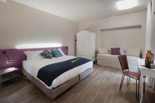 a bedroom with two beds and a table and a chair at Angolo Divino in Alba