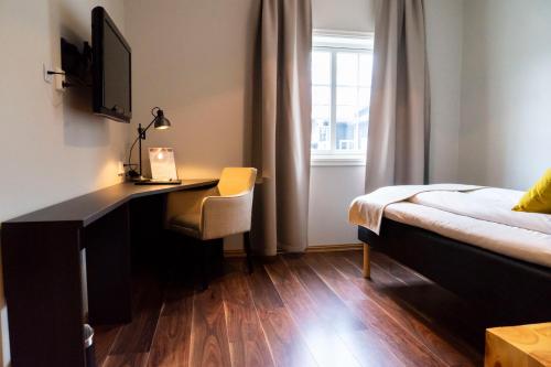 a bedroom with a desk and a bed and a window at Vollan Gjestestue in Nordkjosbotn