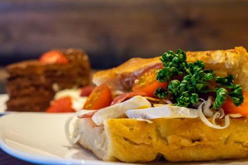 a white plate with a sandwich with vegetables on it at Vollan Gjestestue in Nordkjosbotn