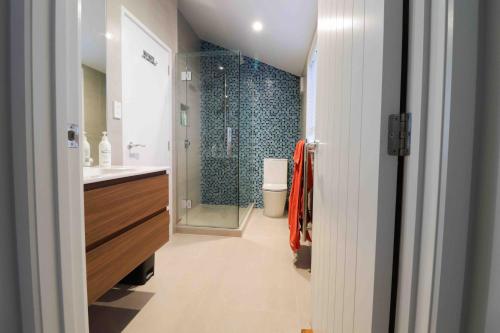 La salle de bains est pourvue d'une douche, d'un lavabo et de toilettes. dans l'établissement Halfmoon Bay Apartment, à Auckland