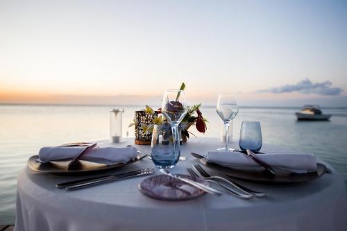 a table with a white table cloth and silverware and a table with the ocean at Radisson Blu Resort, Fujairah in Dibba