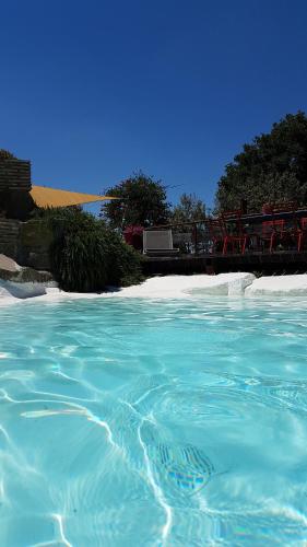 a pool of turquoise blue water next to a beach at Piccolo Feudo Green Resort in Viterbo