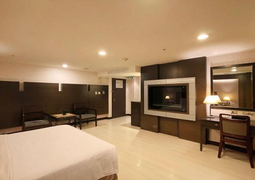 a hotel room with a bed and a tv and a kitchen at Shihzuwan Hotel – Kaohsiung Station in Kaohsiung