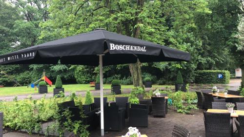 un ombrellone nero con tavoli e sedie in un parco di Hotel Restaurant Het Witte Paard a Delden