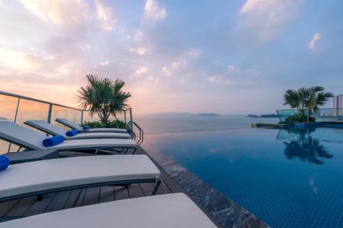 ニャチャンにあるBoton Blue Hotel & Spaの背景に海を望むプール(椅子付)