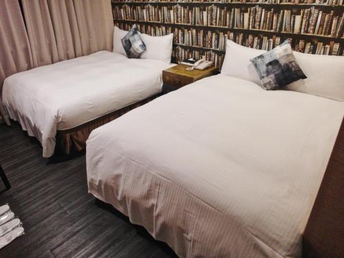 two beds in a room with a book shelf at Hotel Fun - Linsen in Taipei