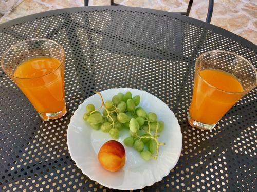 a plate of fruit on a table with two glasses of orange juice at Luxury Villa Minerva Gardens in Split