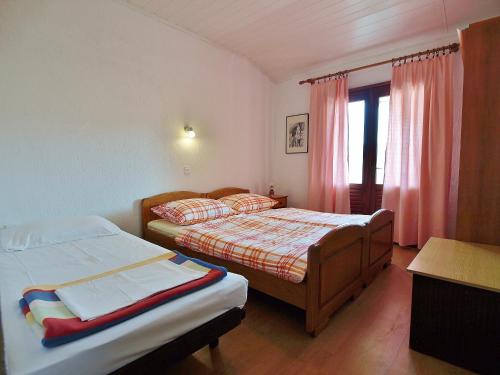 a bedroom with two beds and a window at Apartmani Danijela Lopar in Lopar