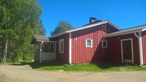 a red house with a white door next to a dirt road at Maatilamatkailu Jänisvaara in Kolinkylä