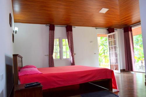 a bedroom with a bed with a red blanket at Sama Uyana Holiday Bungalow in Gampola