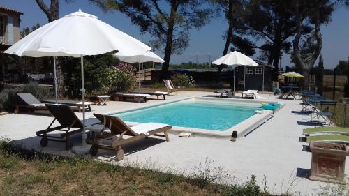 a swimming pool with chairs and umbrellas and a swimming pool at La Coudoulière in Saint-Rémy-de-Provence