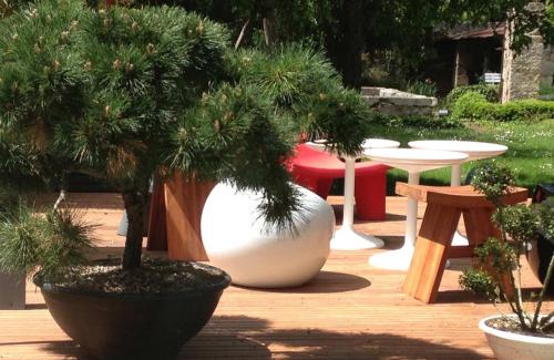 a group of potted trees in a garden with tables and tables at La Maison Arouet in Saint Loup Lamaire