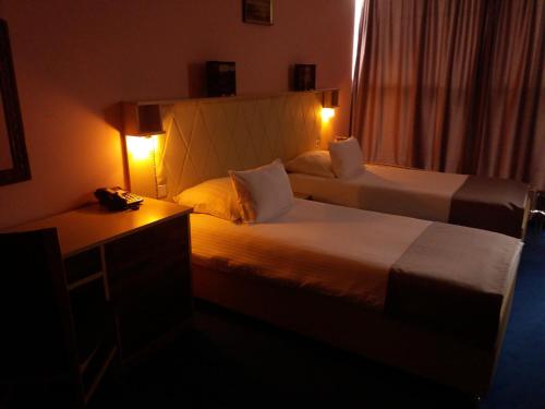 a hotel room with two beds and a phone on a desk at Hotel & Restaurant Great Wall - Airport in Sarajevo