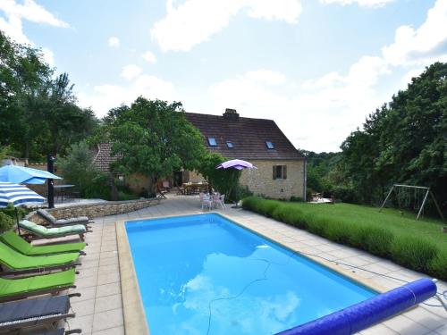 Villefranche-du-PérigordにあるSuperb Holiday Home in Busse with Swimming Poolの芝生の椅子と家のあるスイミングプール