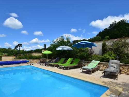 Villefranche-du-PérigordにあるSuperb Holiday Home in Busse with Swimming Poolの芝生の椅子とパラソル付きのスイミングプール