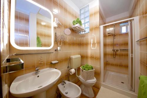 een badkamer met een wastafel, een toilet en een spiegel bij Melanija 2 in Rovinj