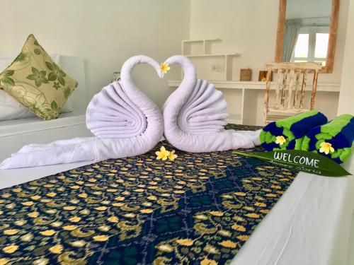two white swans are sitting on a bed at Narayana Homestay in Amed