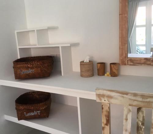 a white shelf with baskets on it next to a window at Narayana Homestay in Amed