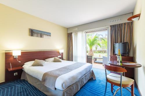 une chambre d'hôtel avec un lit, une table et une fenêtre dans l'établissement Hotel Brise de Mer - Piscine intérieure & extérieure, à Saint-Raphaël