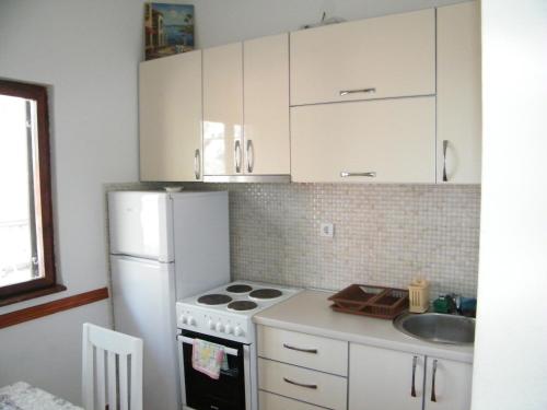 een keuken met een witte koelkast en een wastafel bij Apartmani Mirista in Herceg-Novi