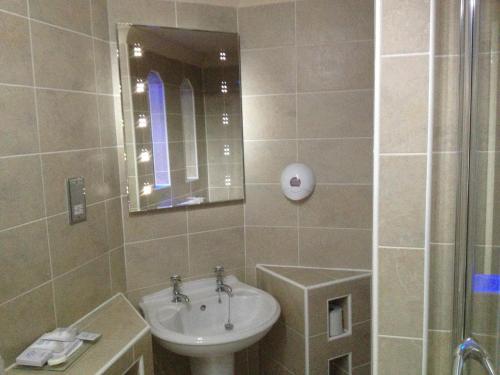 a bathroom with a sink and a mirror and a shower at Rogerthorpe Manor Hotel in Pontefract