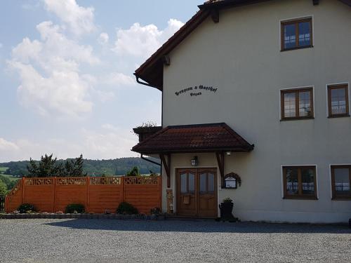 a white building with a brown door and a fence at Pension und Bauernhof Petzold in Greiz