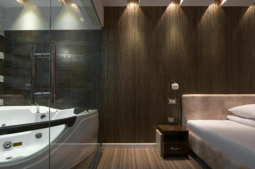 a bathroom with a tub and a bed and a sink at Hotel Ženeva Lux in Kragujevac