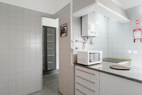 una cucina bianca con forno a microonde su un bancone di Estefânia RoofTop Apartment - Lisbon Center (NEW) a Lisbona