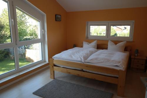 a bedroom with a bed with white sheets and two windows at Ferienhaus Frankstraße 5b in Zinnowitz
