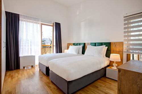 a bedroom with two beds and a large window at Tarcin Forest Resort & Spa Sarajevo - MGallery Collection in Tarčin