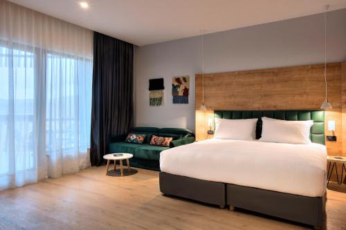 um quarto com uma cama grande e um sofá em Tarcin Forest Resort and Spa MGallery by Sofitel em Tarčin