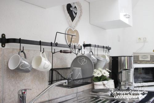 a kitchen counter with cups and utensils on a rack at Korona Apartman Székesfehérvár in Székesfehérvár