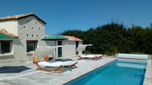 deux chaises et un parasol à côté d'une piscine dans l'établissement Gites du Domaine Maison DoDo, à Lamonzie-Saint-Martin