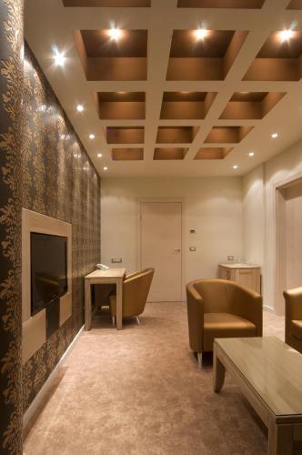 a waiting room with chairs and a tv and a table at Hotel Ženeva Lux in Kragujevac