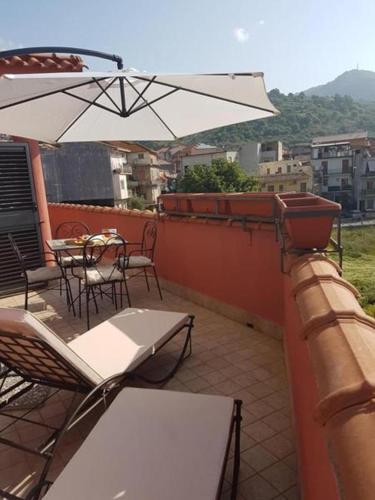 a balcony with tables and chairs and an umbrella at La Porta dell'Alcantara in Gaggi