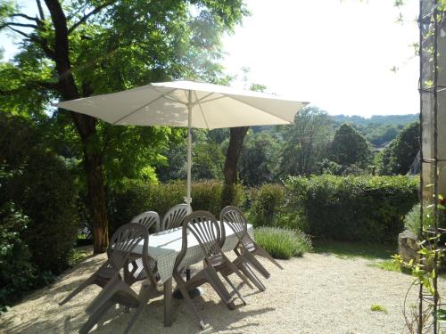 une table et des chaises avec un parasol blanc dans l'établissement La Cave, à Carlux