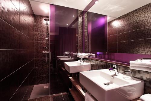 baño con 3 lavabos y espejo con iluminación púrpura en Citiz Hotel, en Toulouse