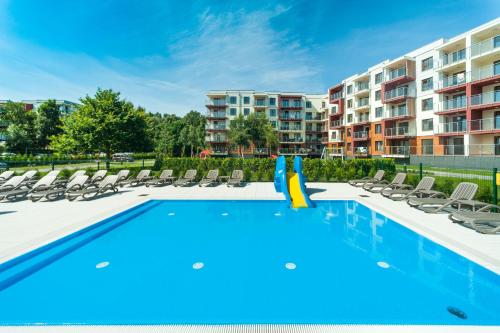 コウォブジェクにあるApartament „Nova Polana” Kołobrzeg Polanki Parkのラウンジチェア付きのスイミングプール、アパートメントを提供しています。